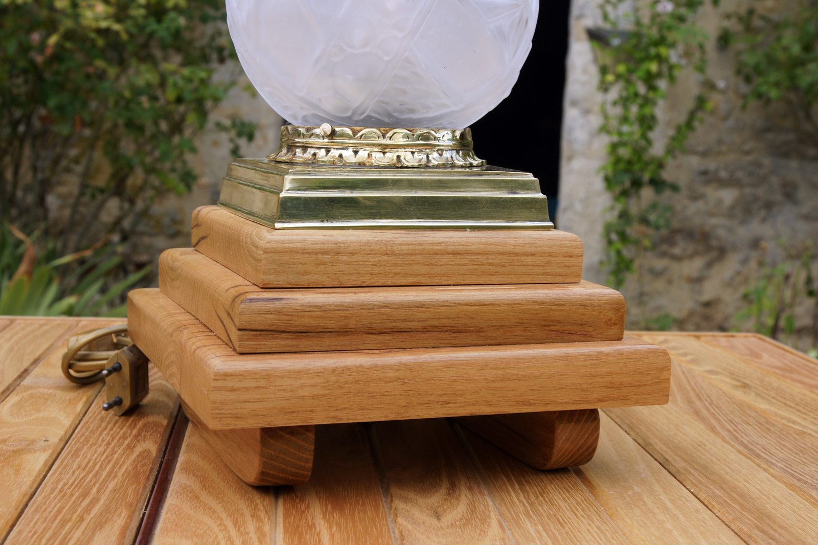 Lampe en bois recyclé, vue de trois quarts sur fond de jardin